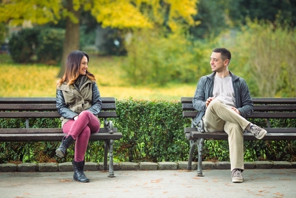 Mann sitzt im Park und Flirtet mit einer Frau