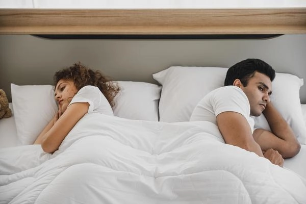 Paar liegt distanziert im Bett bei sexuellen Problemen und fehlender Nähe.