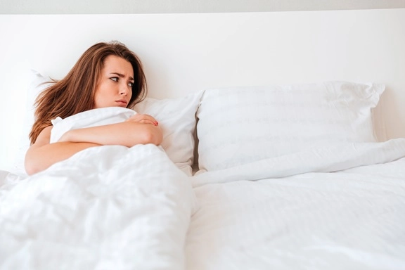 Frau liegt nach einer gemeinsamen Nacht nachdenklich im Bett und wirkt unsicher über die Situation danach.