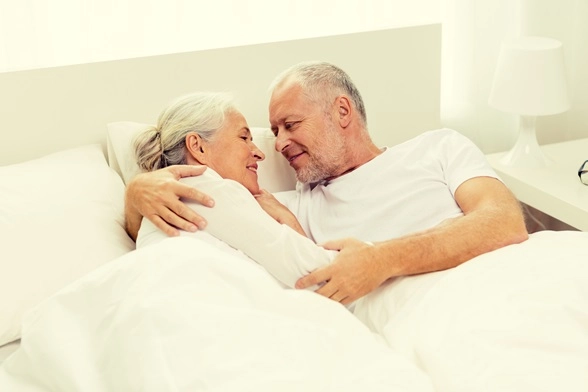 Älteres Paar kuschelt gemeinsam im Bett und zeigt Zärtlichkeit, Vertrauen und ein erfülltes Liebesleben im Alter.